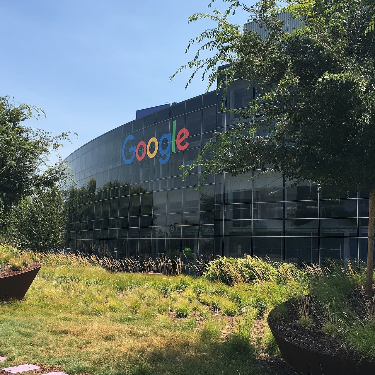 The Googleplex campus, with Android statues on the lawn and the Google logo on a building.